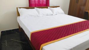 Seetha Residency في تيروفانمالي: غرفة نوم بسريرين مع شراشف بيضاء وحمراء