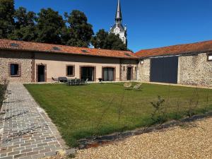 Ein Gebäude mit einem Hof und einem Uhrturm im Hintergrund in der Unterkunft Les Gîtes du Colombier in Ollé