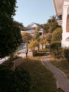 a walkway in a yard with trees and bushes at The Rai Resort Rawai - Pool & Garden in Ban Bang Chak