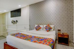 Un dormitorio con una cama grande con sábanas y almohadas de colores. en FabHotel Golden Nest Deluxe - Nr Calangute Beach, en Old Goa