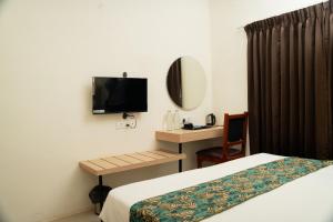 Nillara Kotagiri by Tropic Oasis Hotels في كوتاغيري: غرفة نوم بها سرير ومكتب وتلفزيون