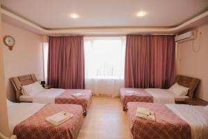 a hotel room with three beds and a window at Hotel Caucasus in Tbilisi City