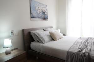 a white bedroom with a bed and a lamp at Casa Laura - Home and Relax Malpensa in Lonate Pozzolo