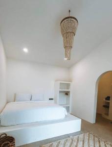 a white bedroom with a white bed and a chandelier at Chic 2BR Villa w/Rock Plunge Pool in Denpasar +8 photos