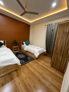 a bedroom with two beds and a ceiling fan at Karma Stay 2BHK apartments in Jaigaon