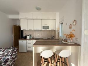 a kitchen with white cabinets and a counter with stools at BlueCoast Apartment in Herceg-Novi +21 photos