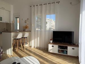 a living room with a flat screen tv and a kitchen at BlueCoast Apartment in Herceg-Novi
