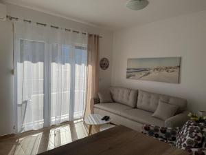 a living room with a couch and a large window at BlueCoast Apartment in Herceg-Novi