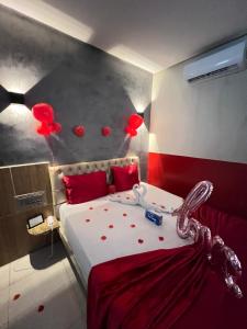 a bedroom with a bed with red pillows and balloons at Eros Motel in Natal