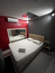a bed in a room with a red wall at Eros Motel in Natal