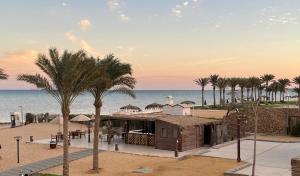 a building on the beach with palm trees and the ocean at Luxury Chalet in Mountain View 2 , El-Sokhna with Sea View , Pool View and Garden View Families Only "Heated Pool" in Ain Sokhna