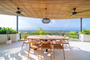 a wooden table and chairs on the balcony of a house at Casa Daria Sofia - Ocean Views Infinity Pool Escape with Cinema & Gym in Uluwatu