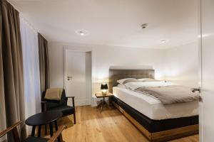 Maximilian Apartments Lindau في لينداو: غرفة نوم بها سرير وكرسي