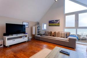een woonkamer met een bank en een flatscreen-tv bij The Deck House - St Monans in Saint Monance