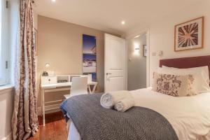 een slaapkamer met een groot bed met een bureau en een bureau bij The Deck House - St Monans in Saint Monance