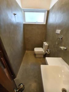 um banheiro com vaso sanitário, pia e janela em Tabbowa Lake Resort em Nikawatawana