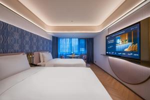 a hotel room with two beds and a flat screen tv at Manxin Hotel Beijing Guomao Jianguomen in Beijing