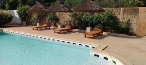 a swimming pool with chairs and umbrellas next to a swimming pool at Le Ganalé in Warang