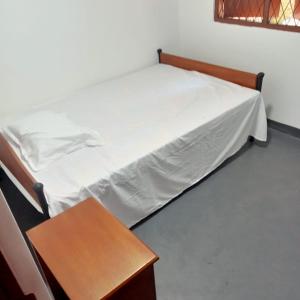 a bed in a room with a wooden table at Cenesco Rest in Induruwa +2 photos