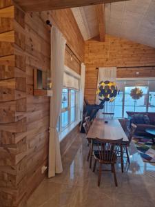 a dining room and living room with a wooden wall at ArcticStay Timmerstugan in Gällivare