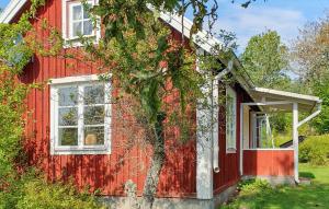 una casa roja con un árbol delante en 2 Bedroom Amazing Home In Fagerhult, en Bockasjögle
