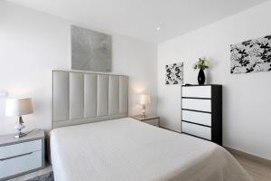een witte slaapkamer met een bed en twee nachtkastjes bij Natalina T1 in Pederneira