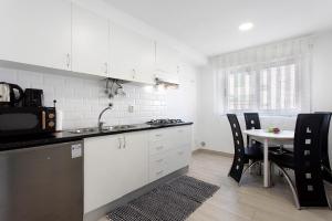 een keuken met witte kasten en een tafel met stoelen bij Natalina T1 in Pederneira