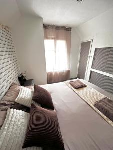 a bedroom with a large white bed with a window at Atypique, calme & cosy, proche de Paris in Bonneuil-sur-Marne