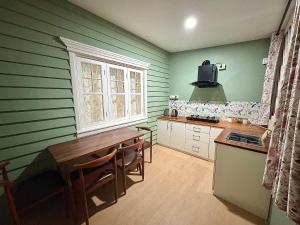una cucina con pareti verdi, tavolo e finestra di Deliana s Homestay a Dithur