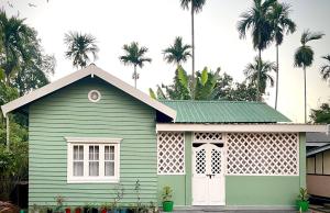 una casa verde con palme sullo sfondo di Deliana s Homestay a Dithur