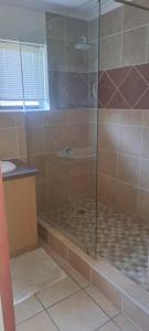 a shower with a glass door in a bathroom at Outeniqua Strandwoonstel in Great Brak River