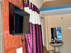 a television hanging on a wall with a curtain at DANDELI NAKADI Home Stay in Dandeli