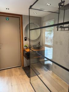 a bathroom with a glass door and a sink at B&B Wellness Garden in Herzele