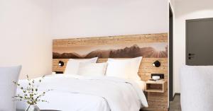 ein Schlafzimmer mit einem großen weißen Bett mit einem hölzernen Kopfteil in der Unterkunft Gästehaus am Hauchen - Adults only in Reit im Winkl