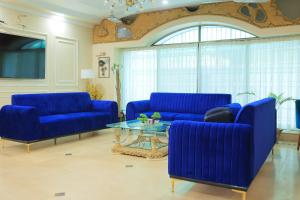 a living room with blue couches and a glass table at Majestic BnB in Karachi