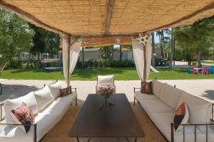 een groep banken en een tafel onder een paviljoen bij Hotiday Otranto Porto in Otranto