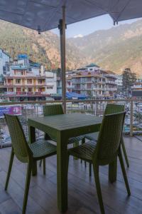 a green table and chairs with a view of a city at Hotel Morainic Hills Mall Road Bhagsunag in McLeod Ganj