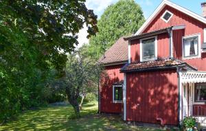 a red house with a tree in front of it at 1 Bedroom Amazing Apartment In Hultsfred in Hultsfred