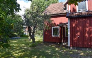 a red house with a tree in the yard at 1 Bedroom Amazing Apartment In Hultsfred in Hultsfred +2 photos