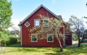 a red house with a tree in front of it at 1 Bedroom Amazing Apartment In Hultsfred in Hultsfred
