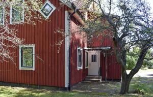a red building with a white door and a tree at 1 Bedroom Amazing Apartment In Hultsfred in Hultsfred