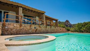 a swimming pool in front of a house at Futura anima sarda, villa sul tramonto con piscina privata in Costa Paradiso