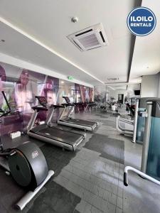 Luxury 1-Bedroom Stay at Saint Honore في Mandurriao: صالة ألعاب رياضية مع أجهزة المشي وأجهزة بيضاوية