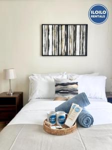 Luxury 1-Bedroom Stay at Saint Honore في Mandurriao: سرير عليه صينية من المناشف والأكواب