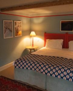 ein Schlafzimmer mit einem Bett und einem Tisch mit einer Lampe in der Unterkunft The Ship in Brancaster