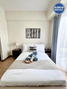 Luxury 1-Bedroom Stay at Saint Honore في Mandurriao: سرير أبيض كبير مع صينية بها أشياء +13 صورة