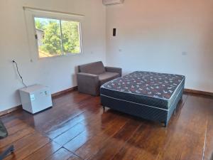 a bedroom with a bed and a chair and a window at Casa Boraceia Litoral Norte SP in São Sebastião