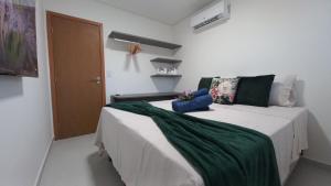 a bedroom with a bed with a green blanket on it at Apto Pe na Areia com Piscina Privativa in Ipioca +13 photos