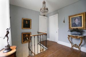 a hallway with a staircase with portraits on the wall and a chandelier at Villa La Poste in Varennes-sur-Amance