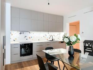 REAL Living by REFA - Modern Haven 1311 في Golčŭv Jeníkov: مطبخ مع طاولة زجاجية مع إناء من الزهور